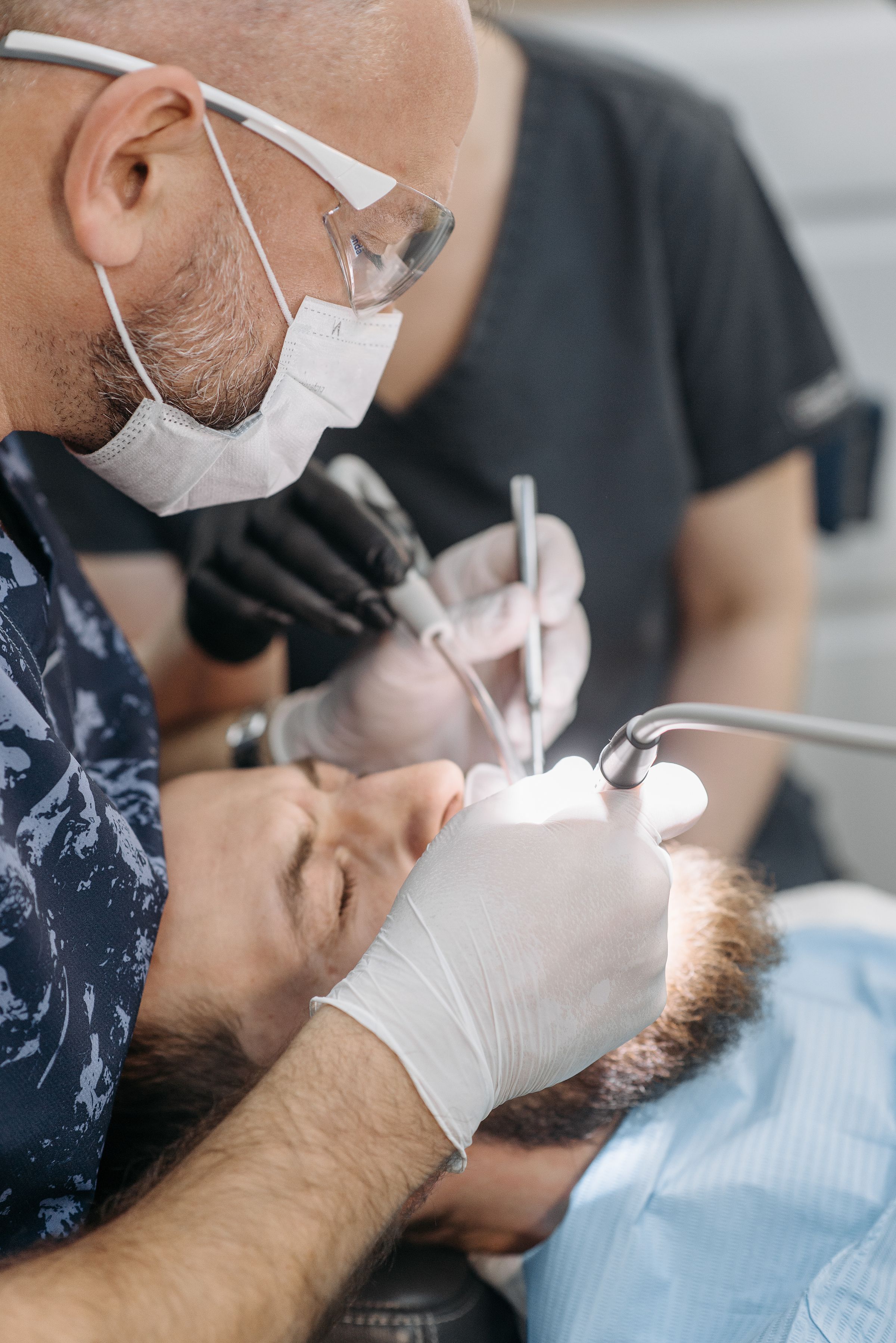 A dentist performs a precise procedure on a patient using a handpiece and explorer.